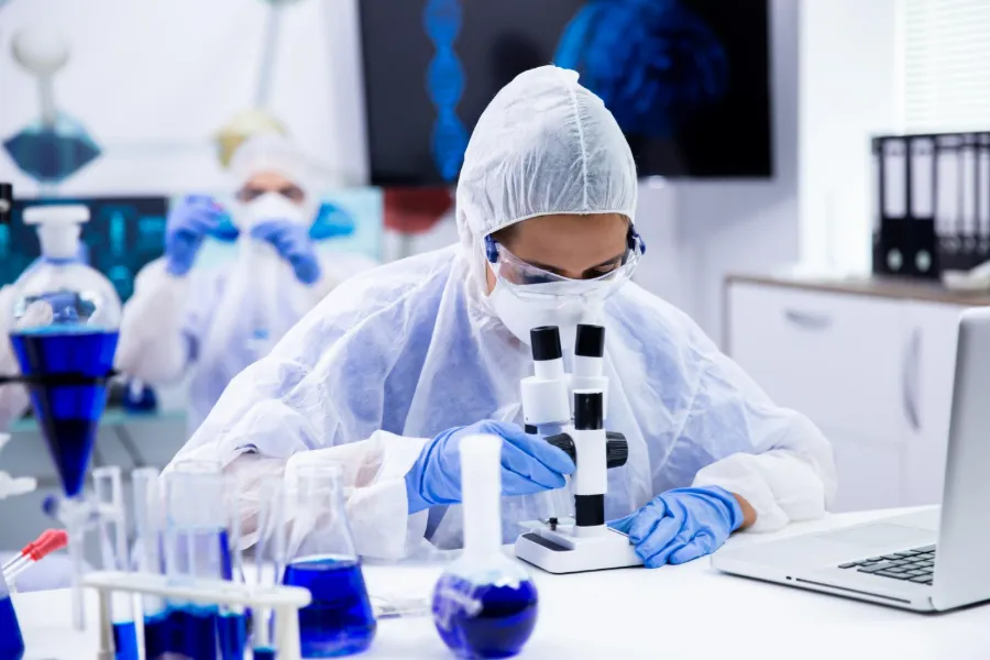 Laborantine en tenue de protection analysant des échantillons